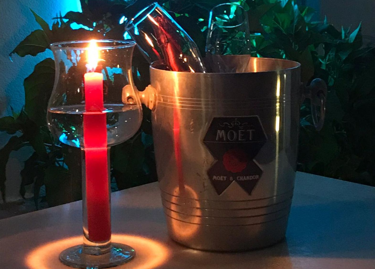 An ice bucket next to a candle with two cava glasses inside